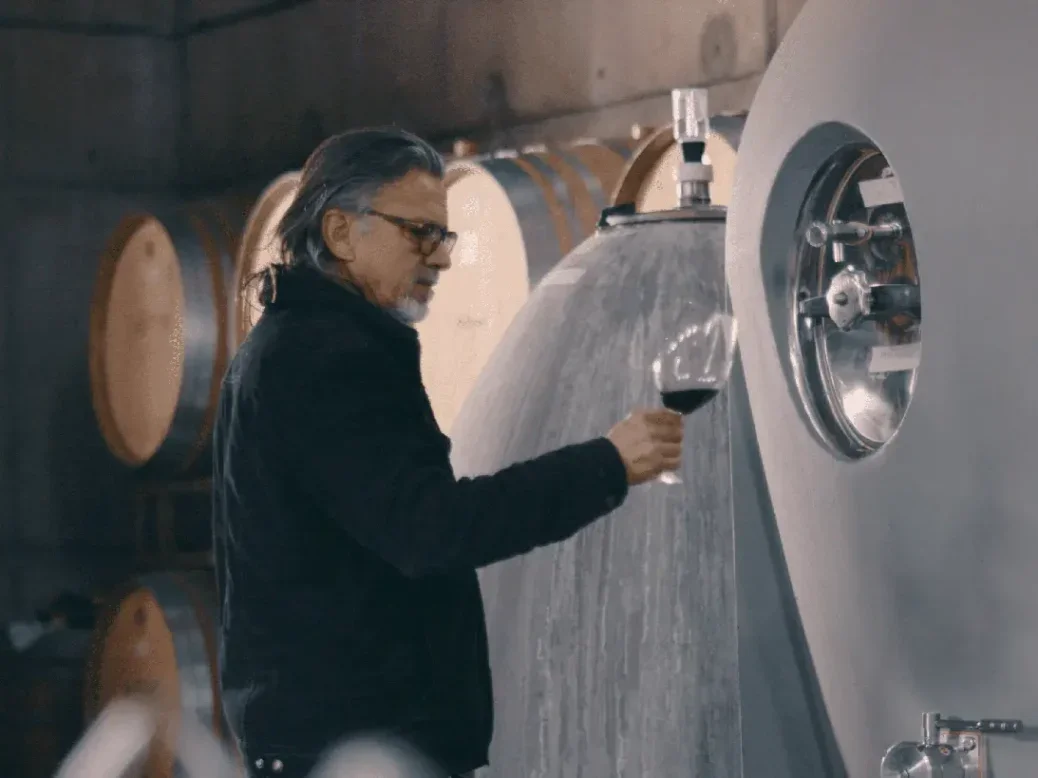 the winemaker Álvaro Espinoza looking at a glass in front of a concrete tank