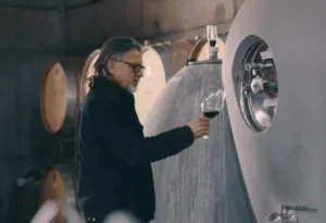 the winemaker Álvaro Espinoza looking at a glass in front of a concrete tank