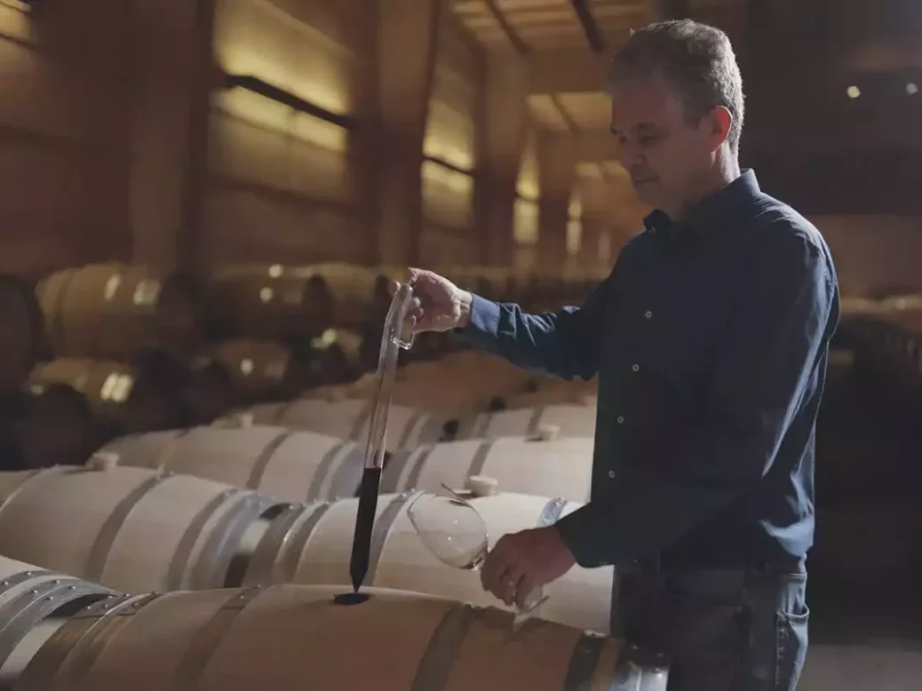 Almaviva winemaker taking a sample from a barrel with a pipette