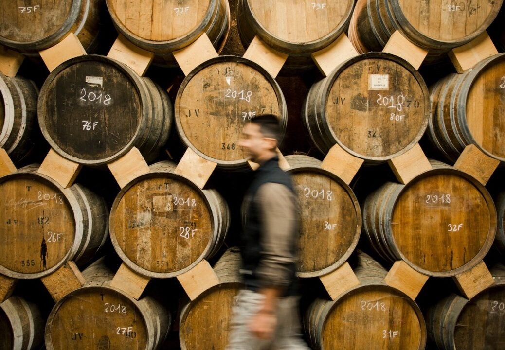 A man walks in front of stacked barrels of Cognac