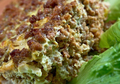 A close-up of a serving of bobotie with a lettuce leaf