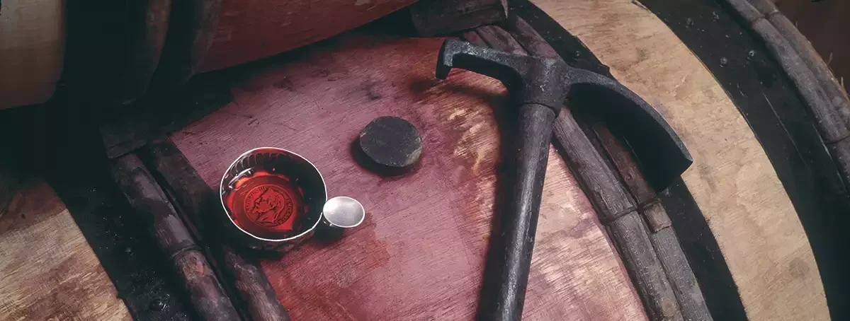 A tastevin cup used for geosensory tasting filled with wine on top of a barrel