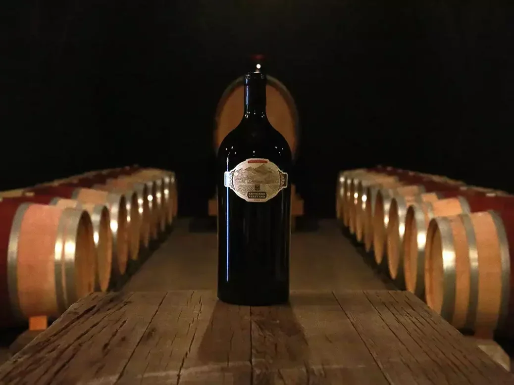 A bottle of Cathiard wine surrounded by barrels in a cellar