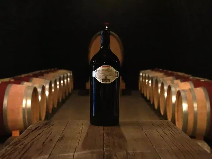 A bottle of Cathiard wine surrounded by barrels in a cellar