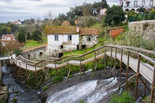 Wooden walkways and little stone houses by a river in Santa Comba Dão.