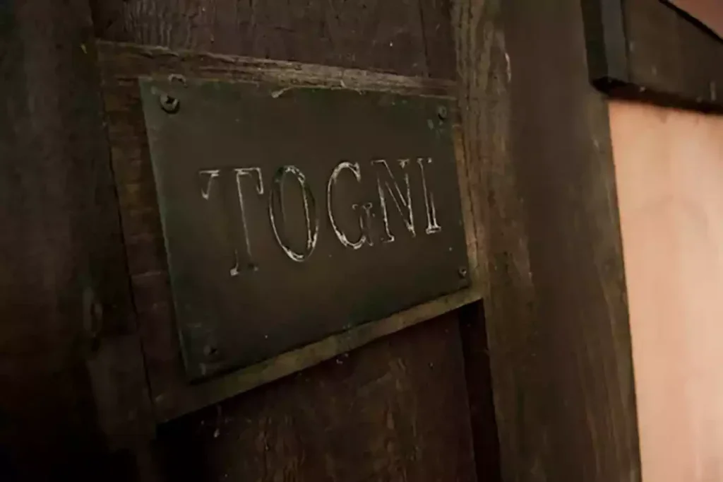 An embossed metal plaque saying Togni on a wooden door