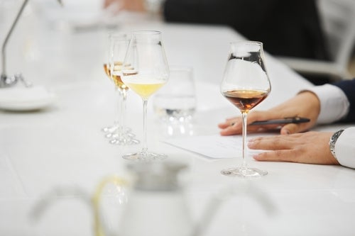 A blind tasting with three glasses of wine on a white table with two hands