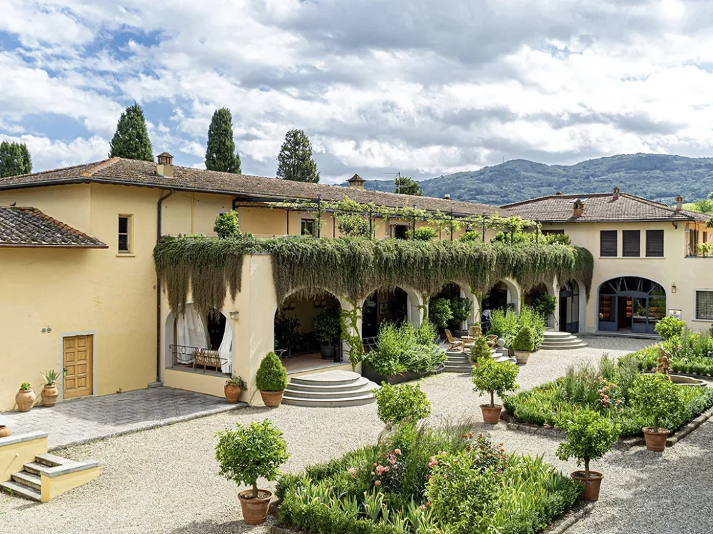 A Tuscan villa painted in warm beige with hedges and paths in the garden