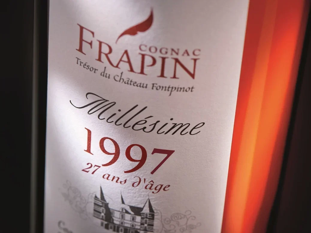 A close up of the label on a bottle of Frapin Millésime 1997 27-year-old Cognac Grande Champagne Premier Cru de Cognac