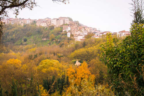 A view of Tufo village on the top of an escarment with autumnal woods in the foreground