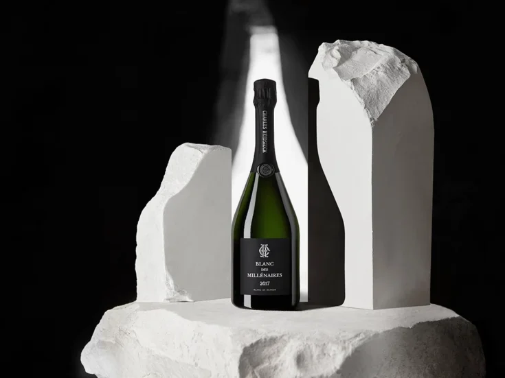 A bottle of Charles Heidsieck Blanc de Millénaires 2017 on a chalk plinth against a black background