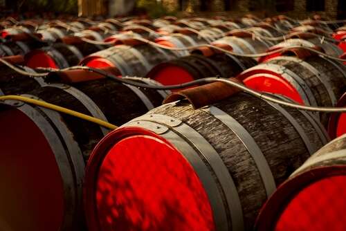 Rows of barrels with red panels on the front and hoses running on the top outside in the sun.