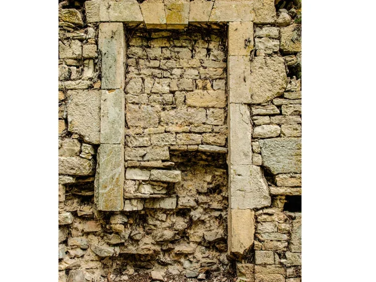 A white stone arch bricked up in a stone wall