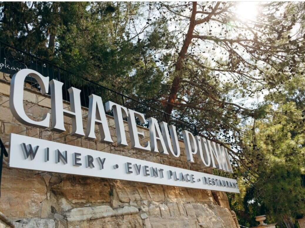 A sign in white saying Château Punin Winery Event Place Restaurant