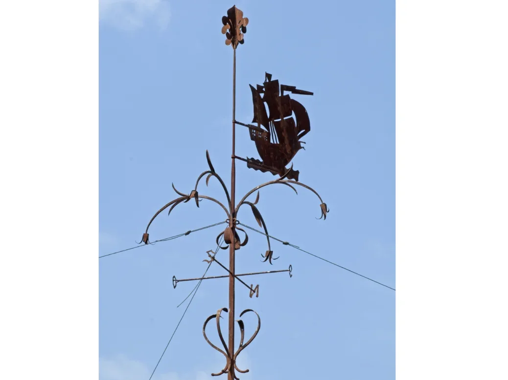 A metal weather frame, elaborate, with a boat silhouette against a blue sky