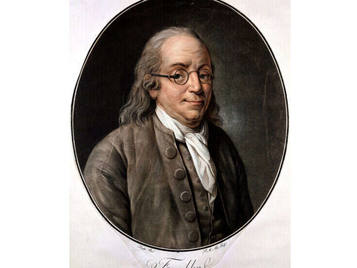 Benjamin Franklin with gentle eyes and round glasses and long grey hair, slightly balding at the top, and with a white silk scarf and grey jacket